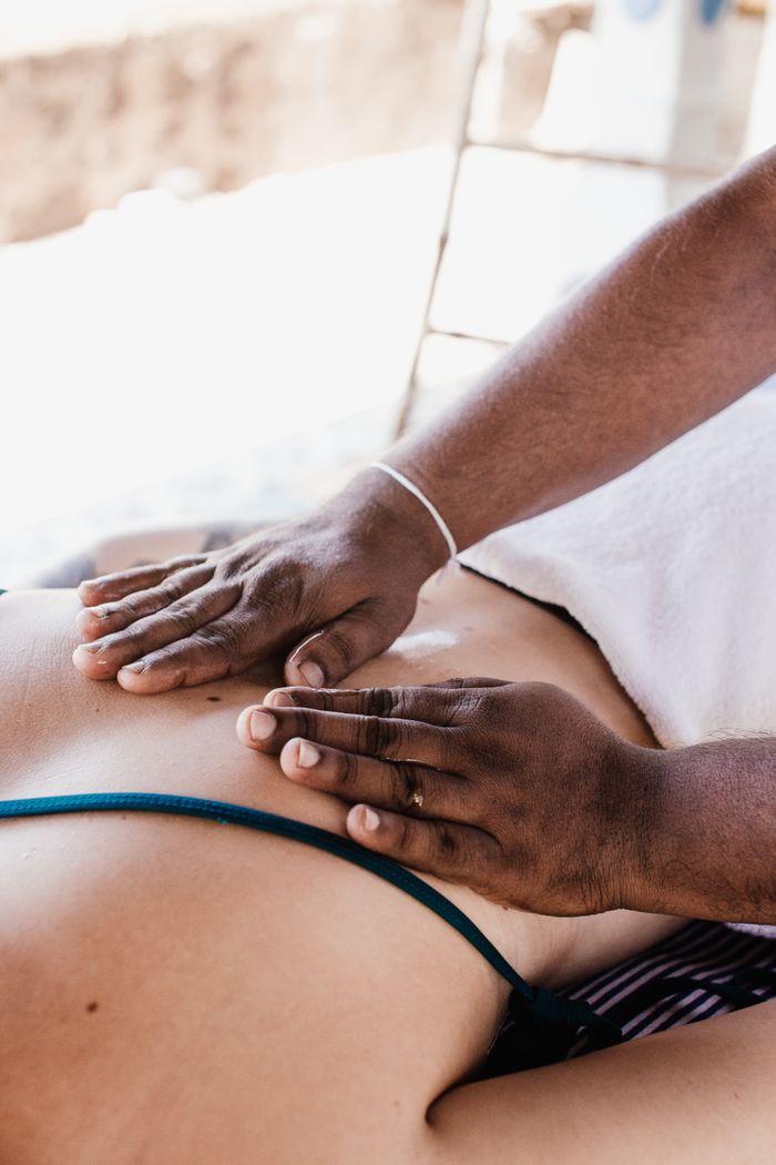 Close-up of a person receiving a back massage outdoors, emphasizing relaxation and wellness.
